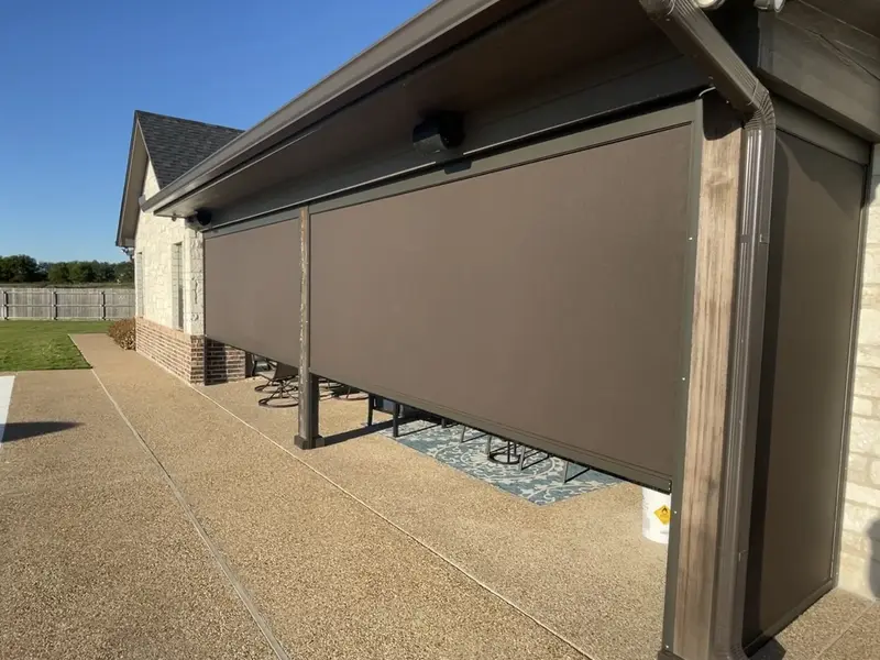 A long run of brown screens lowered along a pool patio on a limestone and brick home.