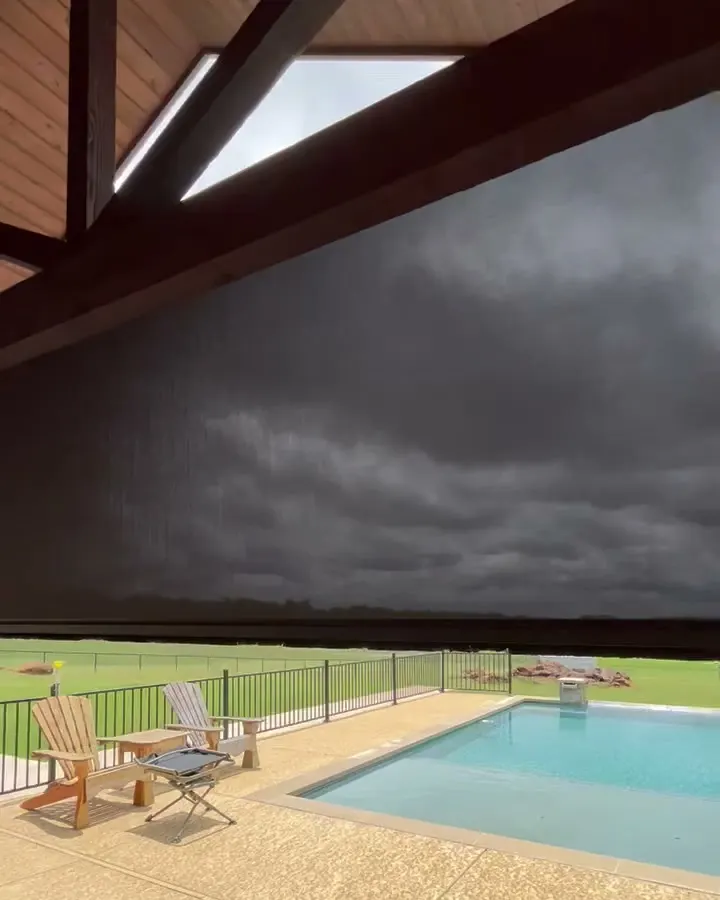 A dark screen halfway down under a cedar ceiling, a pool and lawn chairs on the patio beyond.
